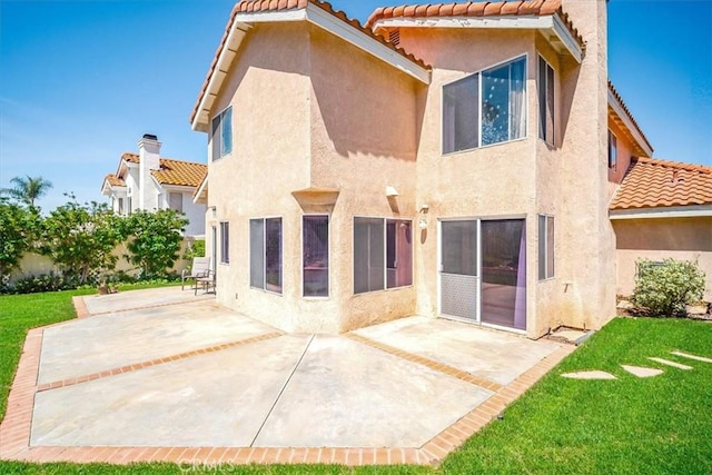 rear view of property with a lawn, stucco siding, and a tiled roof
