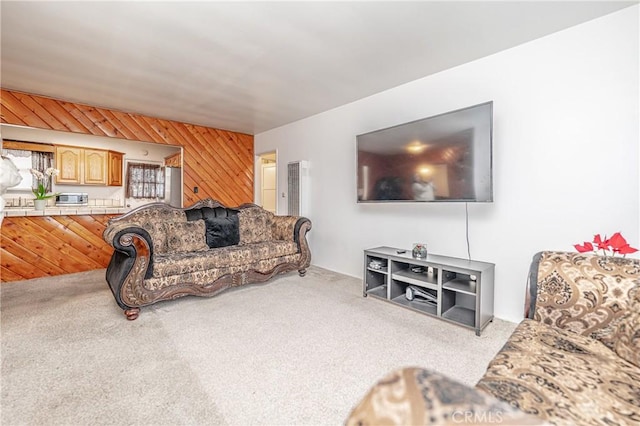 carpeted living room with wood walls