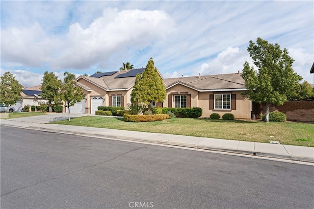 view of front of home with a garage, a front yard, and solar panels