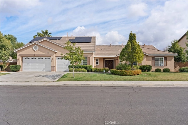 single story home with a garage, a front lawn, and solar panels