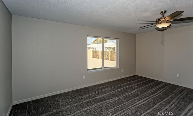 empty room featuring ceiling fan, dark carpet, and a textured ceiling