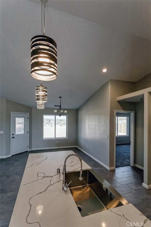 kitchen with pendant lighting, a wealth of natural light, and light stone countertops