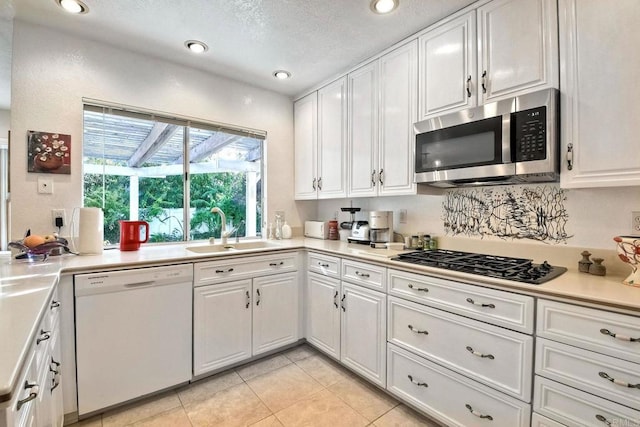 kitchen featuring light tile patterned floors, stainless steel appliances, sink, and white cabinets