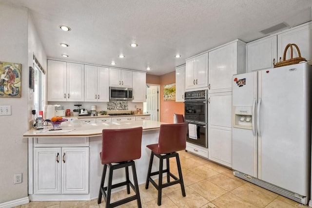 kitchen with a breakfast bar, plenty of natural light, kitchen peninsula, stainless steel appliances, and white cabinets