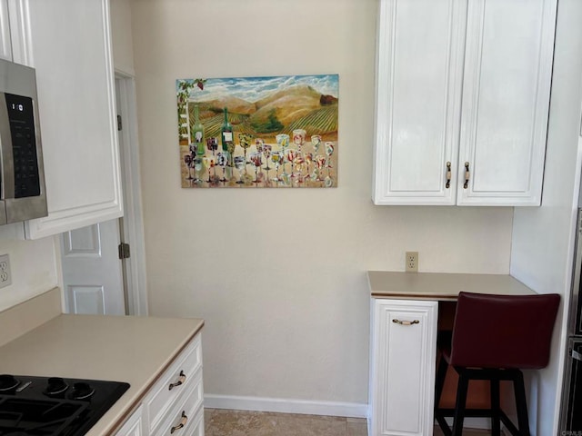 4217 Beach Bluff Rd, Carlsbad, CA 92008 - kitchen featuring stainless steel microwave, white cabinetry, black cooktop, light countertops, and baseboards