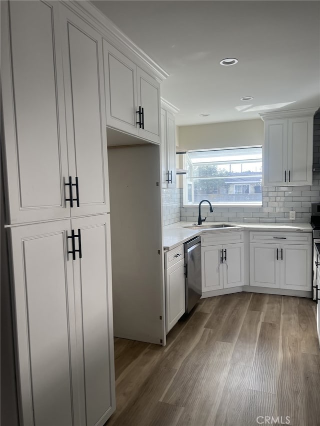 kitchen with sink, stainless steel dishwasher, white cabinetry, and wood-type flooring