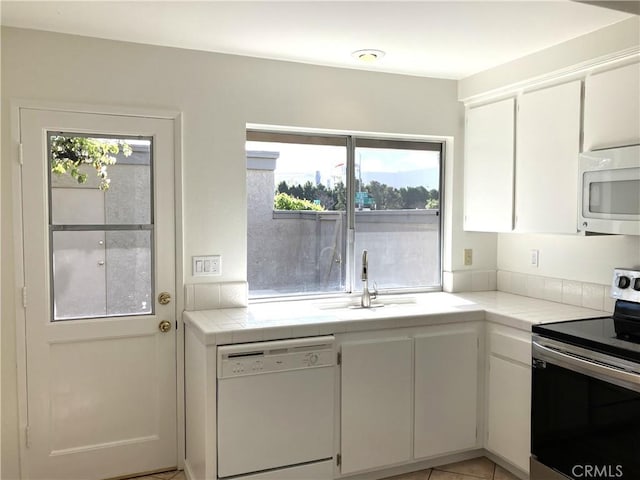 kitchen featuring white cabinetry, sink, white appliances, and tile countertops