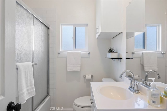 bathroom with vanity, toilet, and bath / shower combo with glass door