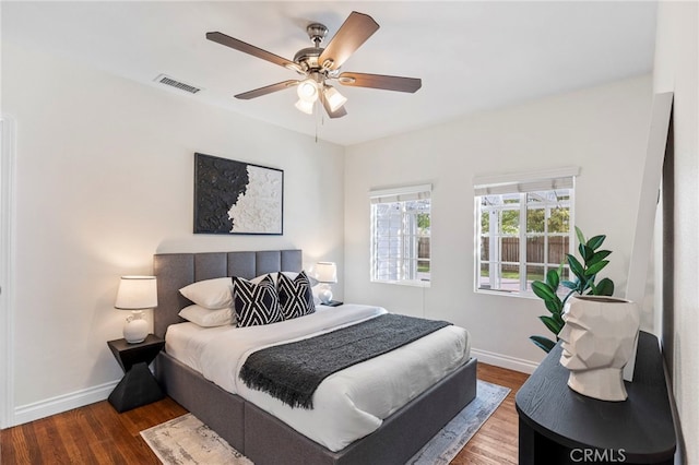 bedroom featuring visible vents, a ceiling fan, baseboards, and wood finished floors