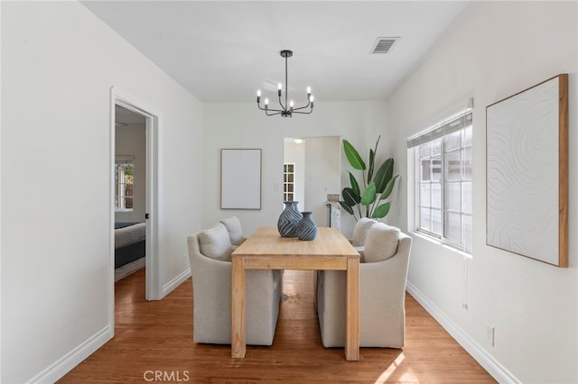 dining room with an inviting chandelier, wood finished floors, visible vents, and baseboards