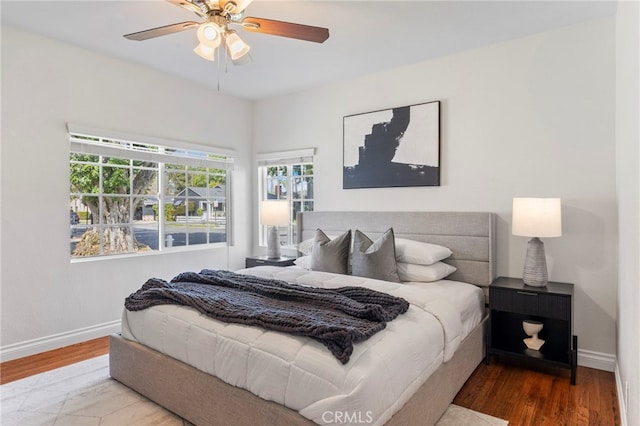 bedroom with baseboards, wood finished floors, and a ceiling fan