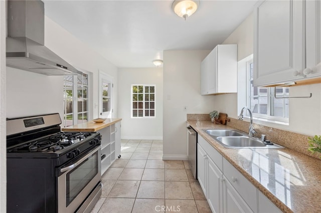 kitchen featuring a sink, white cabinetry, appliances with stainless steel finishes, and wall chimney range hood