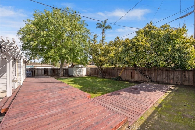 deck featuring a pergola, a fenced backyard, a yard, a storage shed, and an outdoor structure