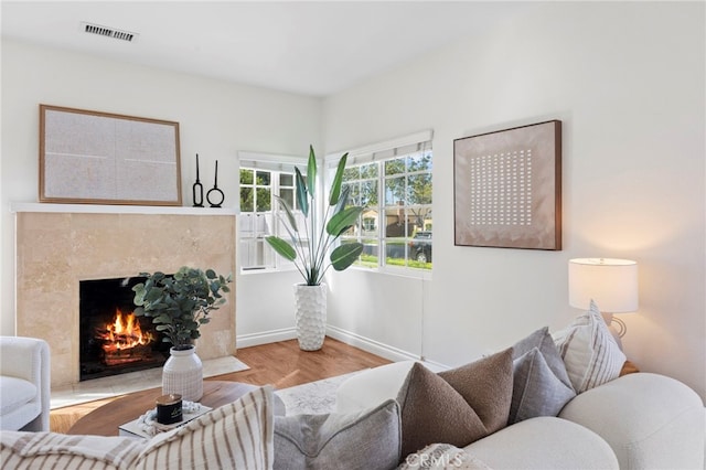 living room with wood finished floors, a fireplace, visible vents, and baseboards