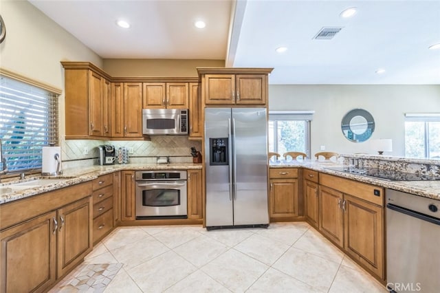 kitchen featuring appliances with stainless steel finishes, sink, backsplash, light tile patterned floors, and light stone counters