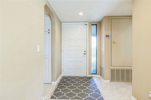 tiled foyer entrance with arched walkways, visible vents, and baseboards