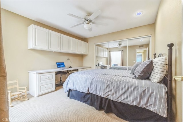 carpeted bedroom with built in desk, ceiling fan, and a closet