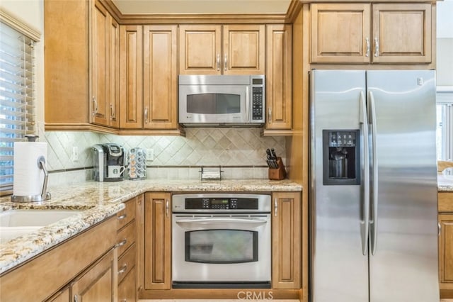 kitchen featuring light stone counters, appliances with stainless steel finishes, and backsplash