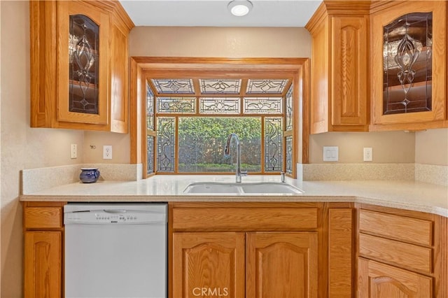 kitchen featuring a sink, glass insert cabinets, white dishwasher, and light countertops