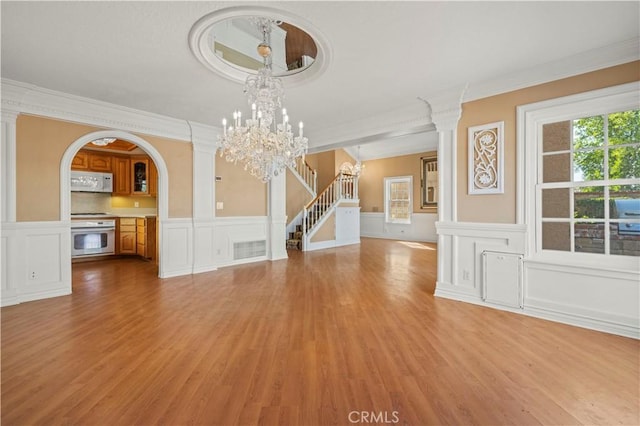 unfurnished dining area featuring stairway, visible vents, arched walkways, light wood-style floors, and a chandelier