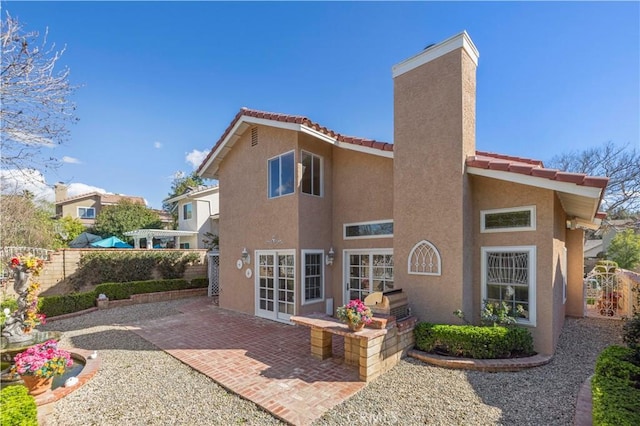 rear view of house featuring fence, a tile roof, stucco siding, french doors, and a patio area