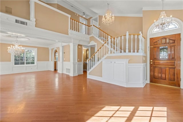 entryway featuring visible vents, crown molding, a chandelier, stairs, and wood finished floors