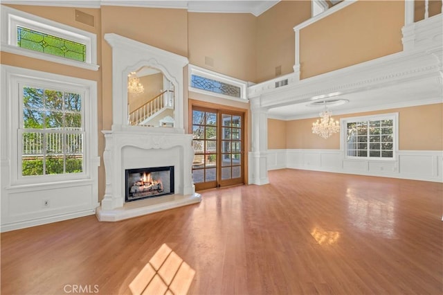 unfurnished living room with a wealth of natural light, a notable chandelier, and a lit fireplace