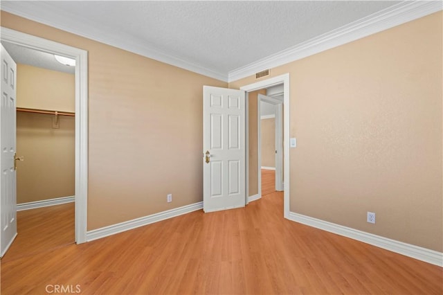 unfurnished bedroom with a closet, visible vents, light wood-type flooring, and baseboards