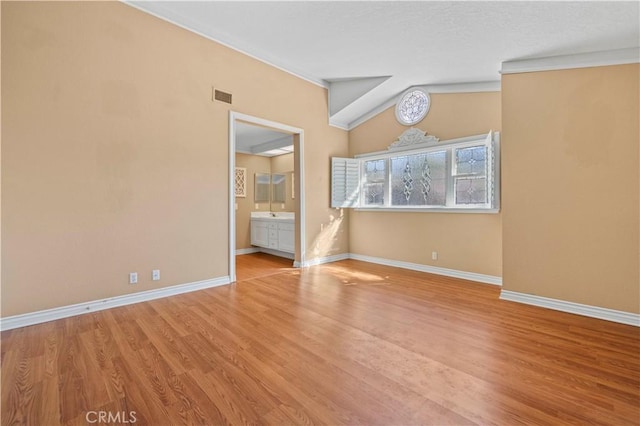 unfurnished bedroom with visible vents, baseboards, lofted ceiling, and light wood finished floors