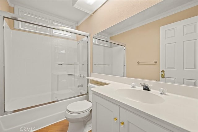 bathroom featuring vanity, wood finished floors, bath / shower combo with glass door, crown molding, and toilet