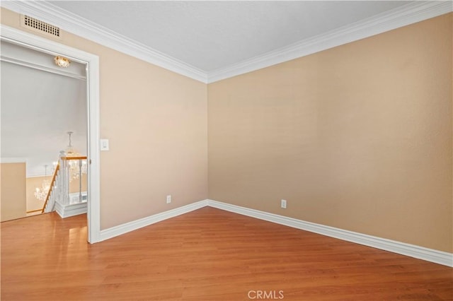 empty room with visible vents, crown molding, baseboards, and wood finished floors