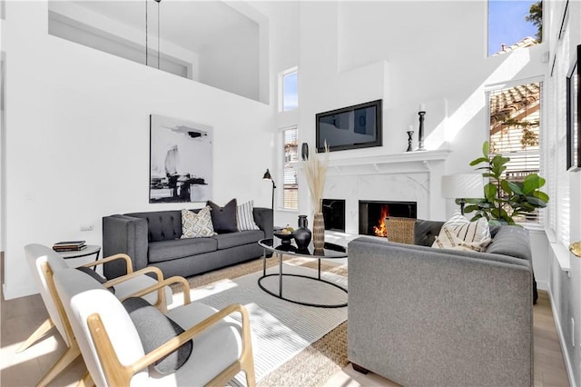 living area featuring a high ceiling, wood finished floors, and a high end fireplace