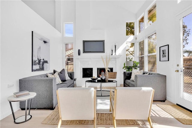 dining room with a high end fireplace, plenty of natural light, a towering ceiling, and wood finished floors