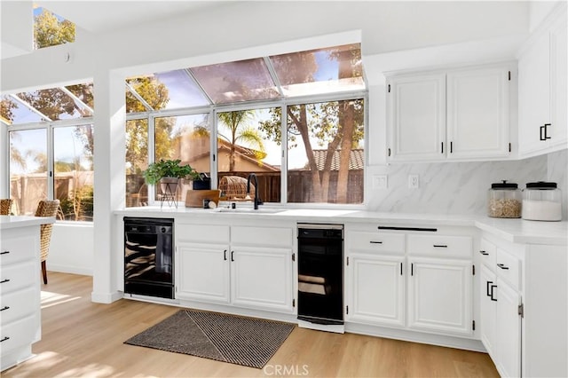 bar featuring light wood-type flooring, a sunroom, decorative backsplash, and a sink