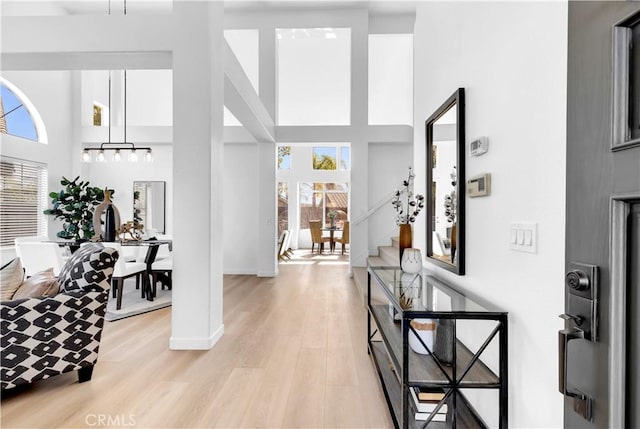 foyer with a towering ceiling, light wood finished floors, stairway, and baseboards