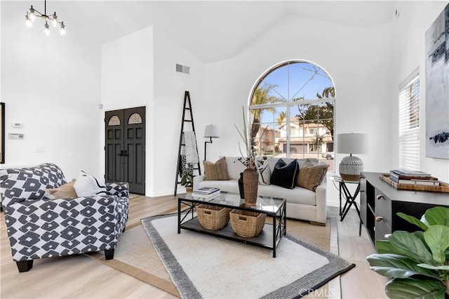 living area featuring high vaulted ceiling, visible vents, and wood finished floors