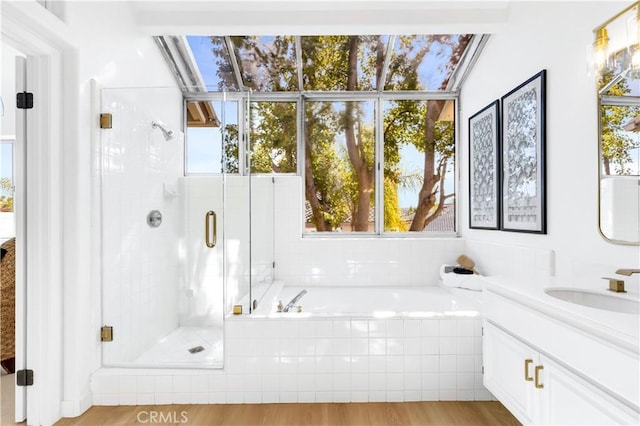 bathroom with a shower stall, wood finished floors, a bath, and vanity