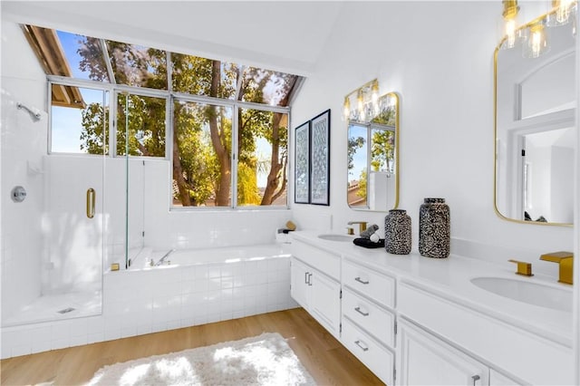 full bath with a garden tub, double vanity, a stall shower, a sink, and wood finished floors