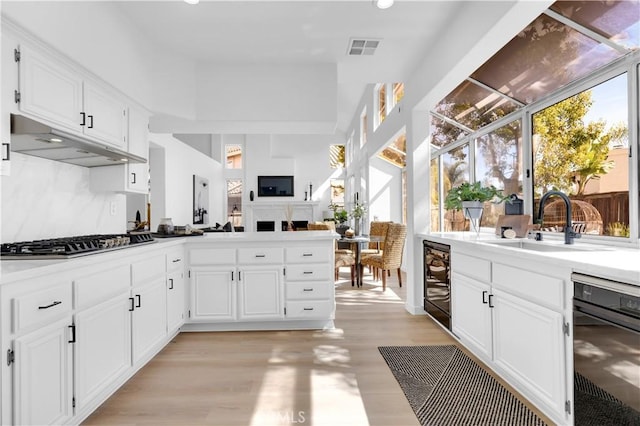 kitchen with beverage cooler, visible vents, under cabinet range hood, stainless steel gas cooktop, and a sink