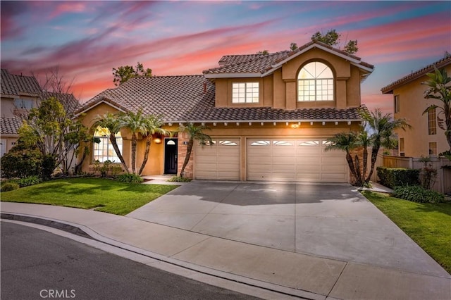 view of front facade featuring a tile roof, a yard, stucco siding, fence, and driveway