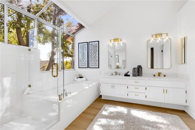 bathroom with a garden tub, wood finished floors, a sink, vaulted ceiling, and a stall shower