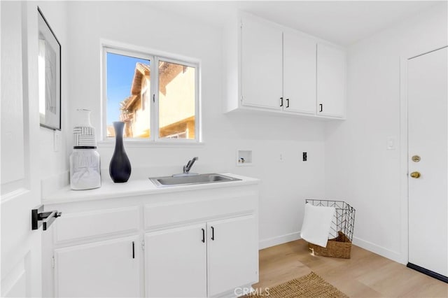 laundry room featuring hookup for a washing machine, light wood-style flooring, a sink, baseboards, and cabinet space