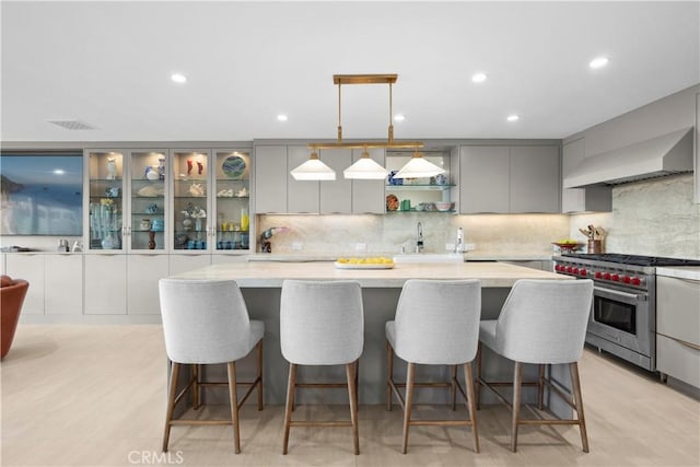 kitchen featuring gray cabinets, a breakfast bar area, high end stove, and decorative light fixtures