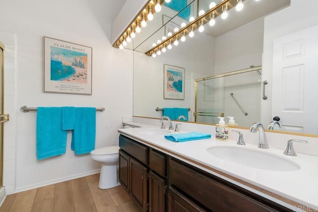 bathroom featuring vanity, toilet, a shower with shower door, and hardwood / wood-style floors