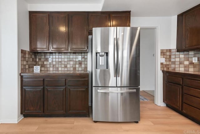 kitchen with dark brown cabinetry, tasteful backsplash, stainless steel fridge, and light hardwood / wood-style floors