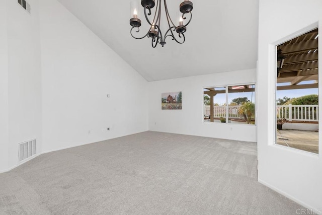 carpeted spare room featuring an inviting chandelier, plenty of natural light, and vaulted ceiling