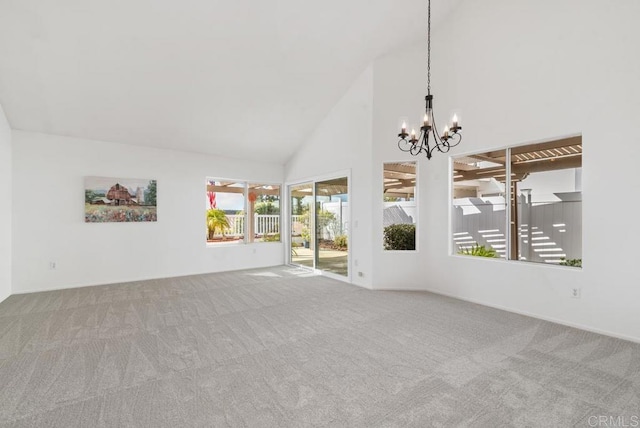 carpeted spare room featuring high vaulted ceiling and a chandelier