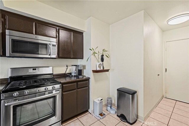 kitchen featuring light tile patterned flooring, dark countertops, appliances with stainless steel finishes, and dark brown cabinetry