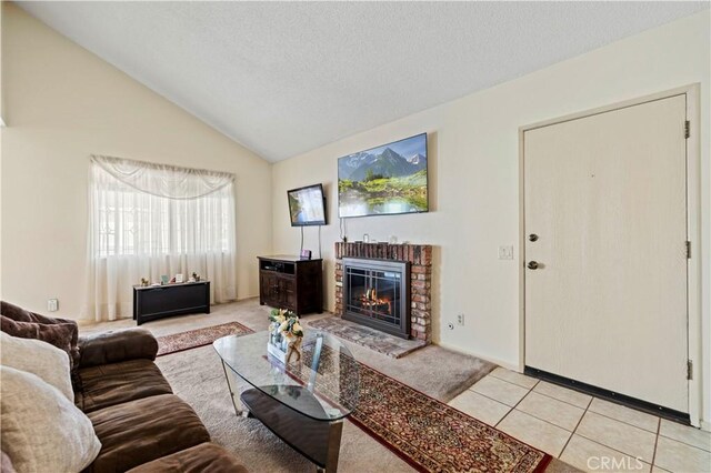 living room with light tile patterned flooring, light carpet, a fireplace, a textured ceiling, and vaulted ceiling