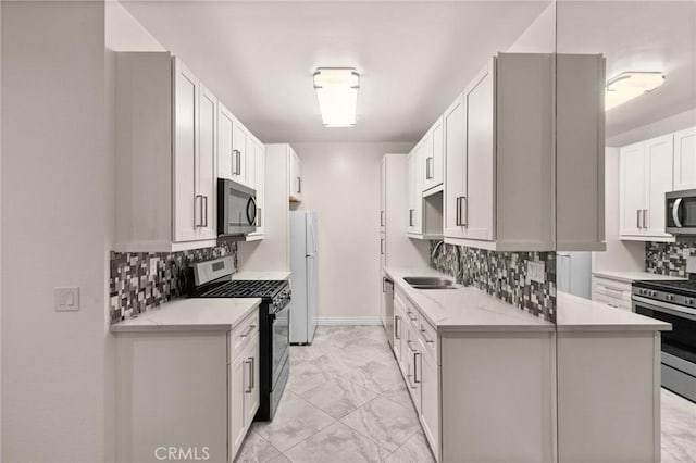 kitchen featuring appliances with stainless steel finishes, sink, backsplash, light stone counters, and white cabinetry